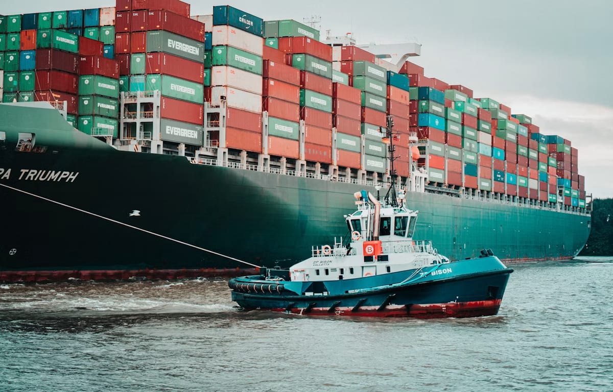 Container ship guided by a tugboat, representing a business expanding into Rwanda through IOR services