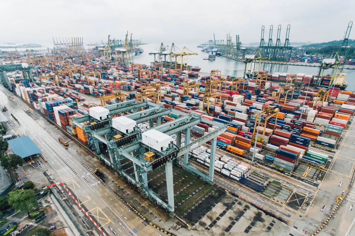 Container port from above with cranes and terminal equipment, showing how imports move through Rwanda-bound supply chains