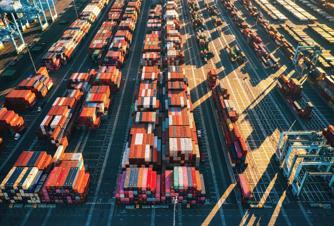Automated container trucks at a terminal seen from above, representing the choice between an IOR and a local importer in Rwanda