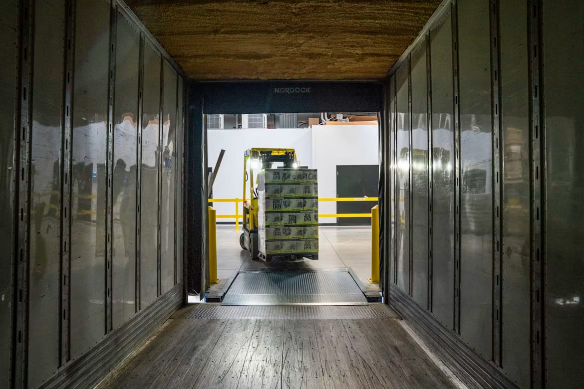 Forklift loading goods at a warehouse dock, representing an importer of record handling cargo in Rwanda